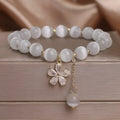White cat's eye stone bracelet with flower tassel detailing and safety buckle closure