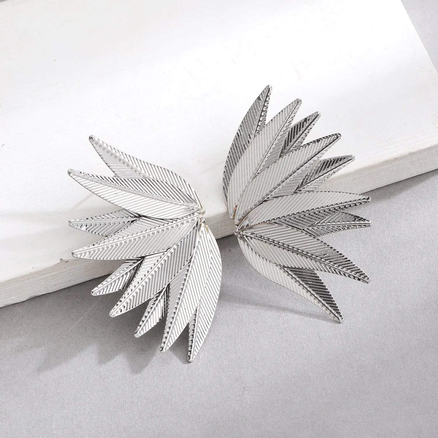 Leaf-shaped patch earrings in gold or white alloy with stud back closure