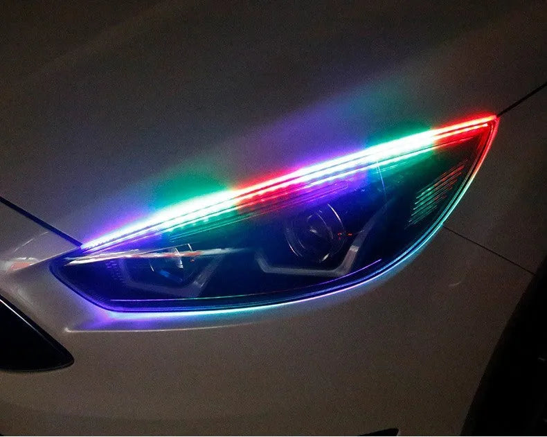 Close-up of a multi-colour RGB LED daytime running light strip with a remote control on a car bumper.