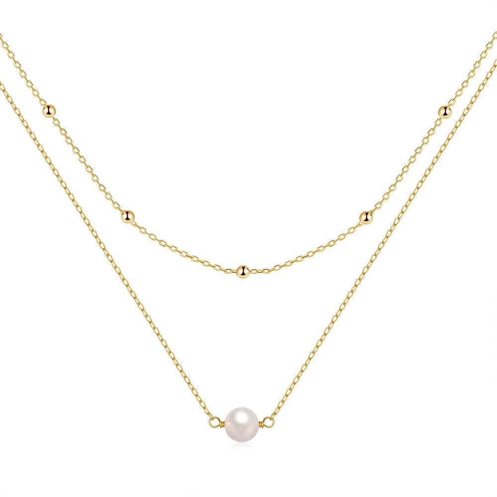 Close-up of a women's double layer sterling silver necklace with two round freshwater pearls on a geometric pendant.
