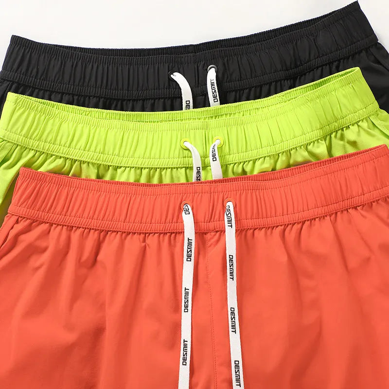Men's loose-fitting beach shorts in orange, fluorescent green, and black colours on a size chart background