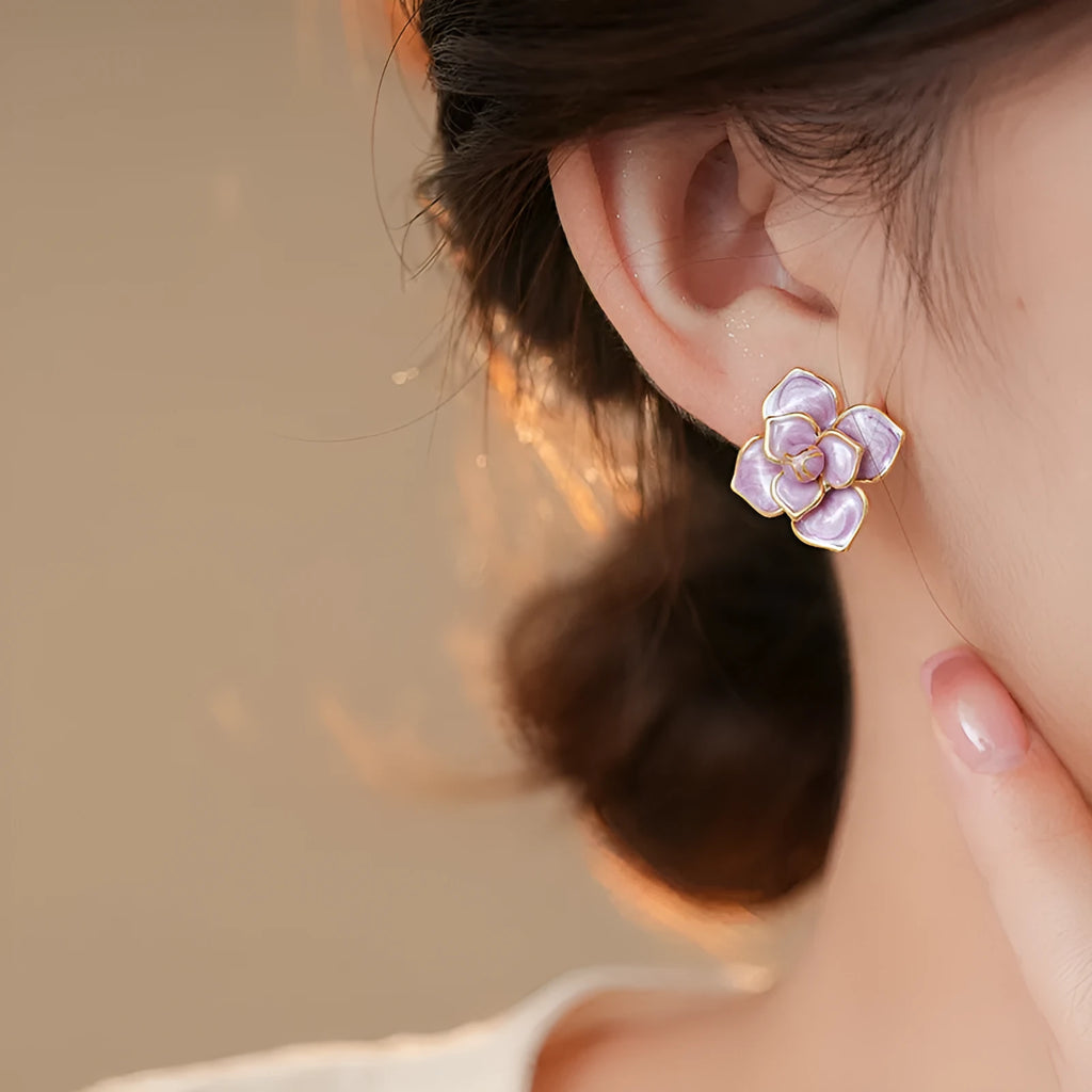 Close-up of gold plated purple oil-spot glaze flower stud earrings on a copper base.