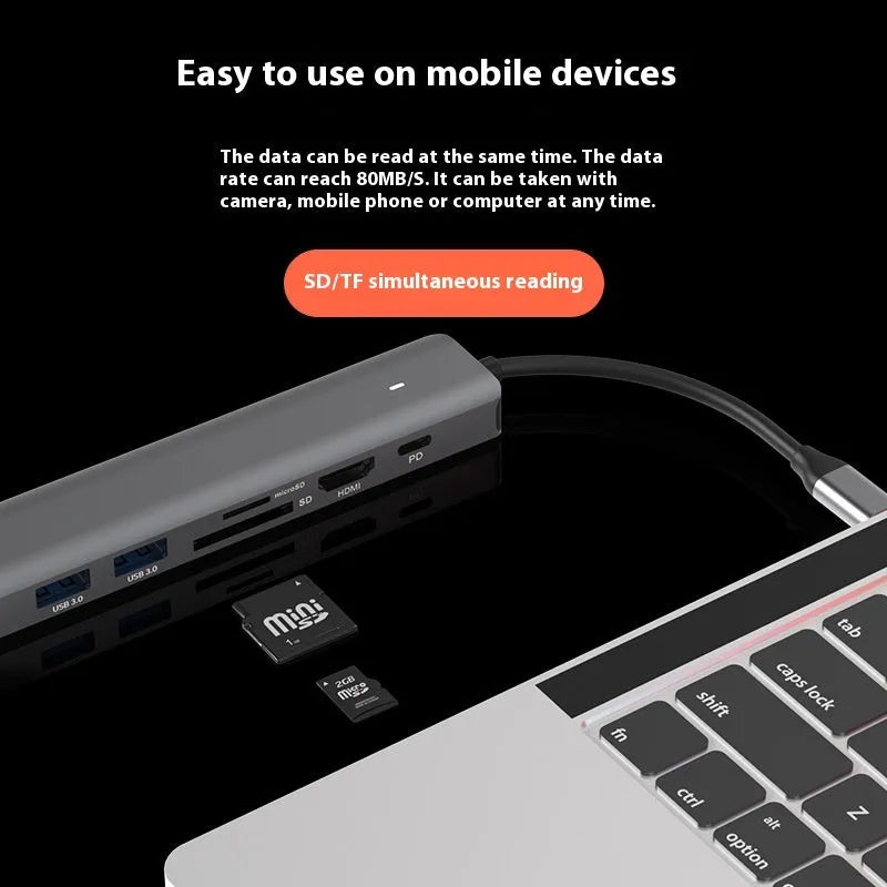 7-in-1 USB C card reader hub with multiple ports and SD card slots on a desk next to a laptop.