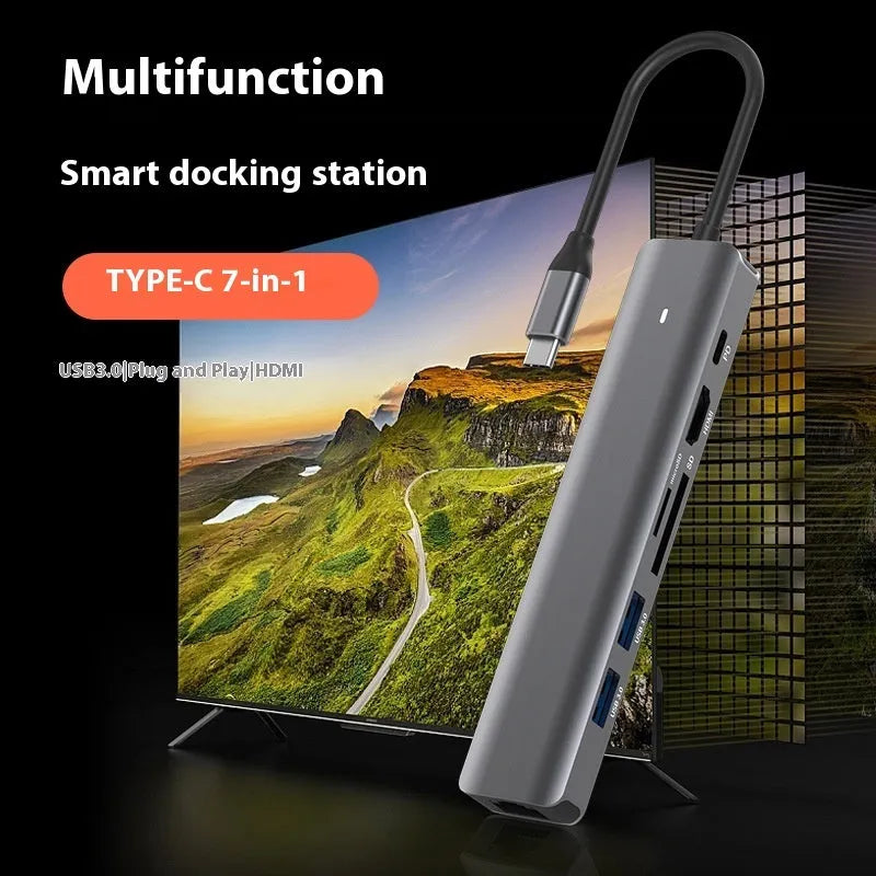 7-in-1 USB C card reader hub with multiple ports and SD card slots on a desk next to a laptop.