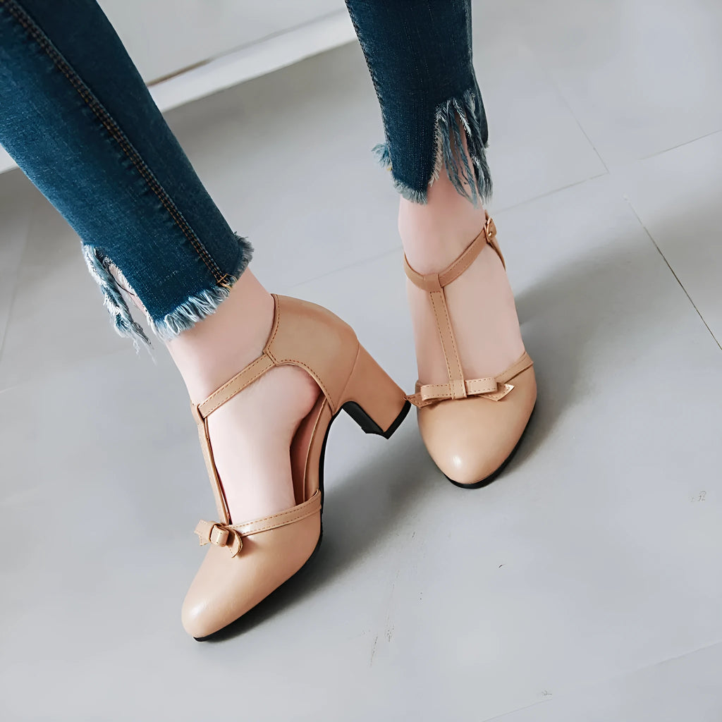 Women's apricot coloured chunky heel sandals with a buckle strap and bow detail on the round toe.