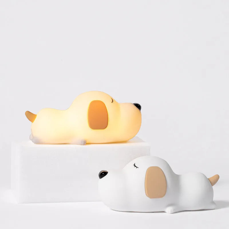 Soft silicone cartoon dog night light with USB cable on a bedside table.