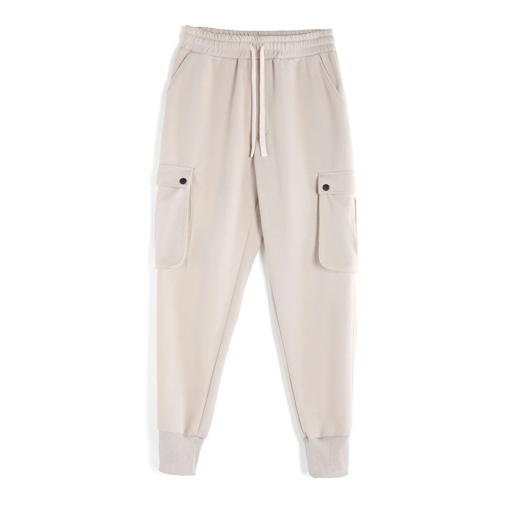 Men's loose-fit beige cotton sports trousers with ankle ties and side pockets laid flat.