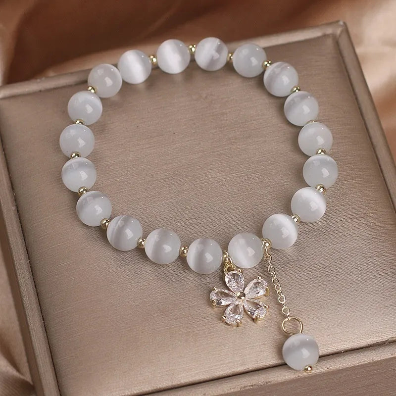 White cat's eye stone bracelet with flower tassel detailing and safety buckle closure