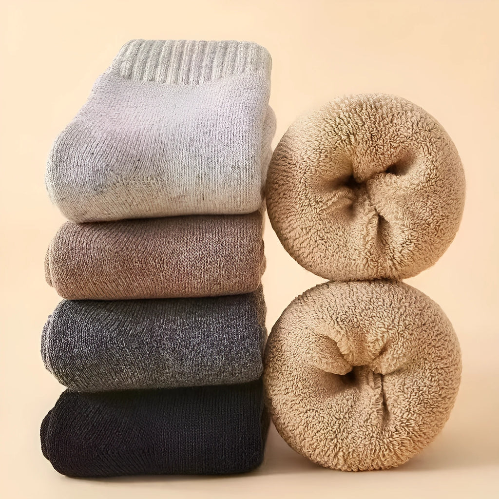 A pair of thick winter wool socks with a Merino midsole in a solid colour, shown next to its presentation box.