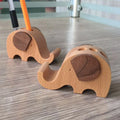 A creative desk mobile phone holder in beech wood or resin animal design with a coin slot.