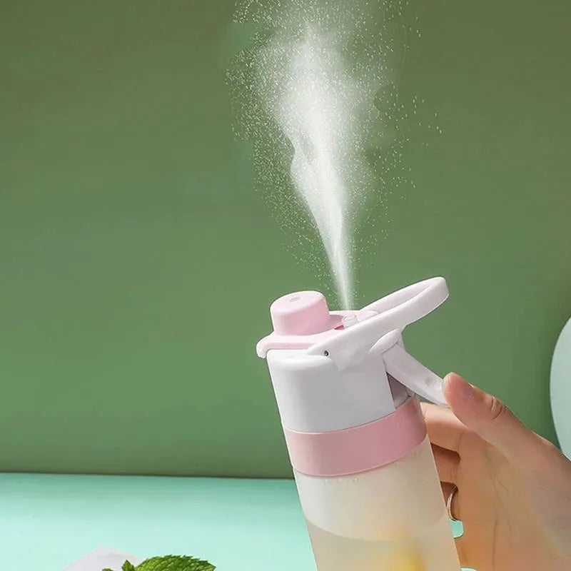 White 700ml plastic spray water bottle with a black handle strap and leakproof lid on a table.