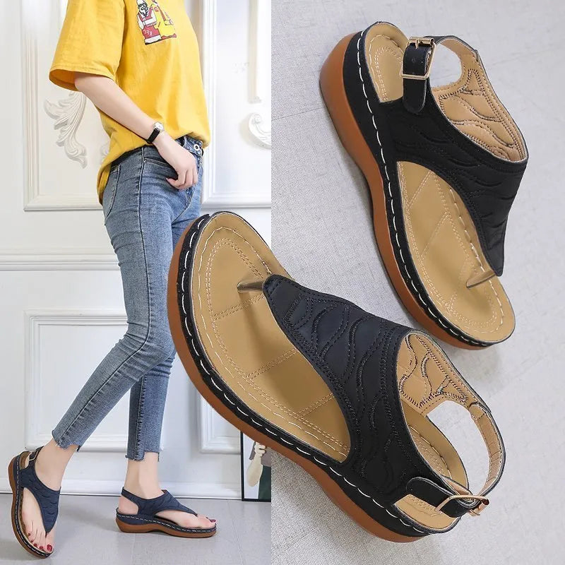 Women's red wedge heel sandals with an adjustable buckle strap on a plain background.