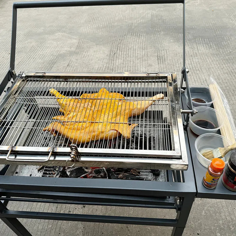 Large portable charcoal barbecue grill with a foldable metal frame set up in a garden.