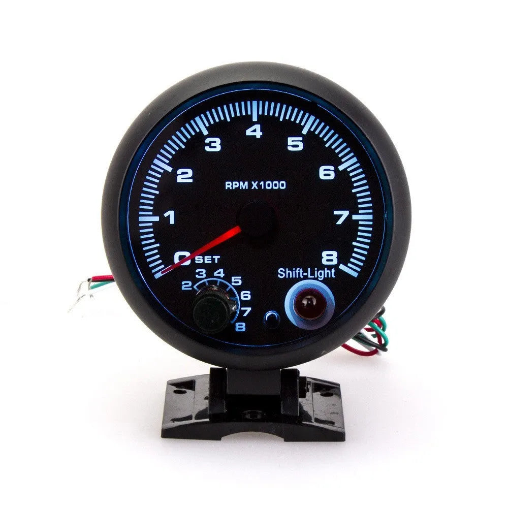 Black plastic automotive tachometer with blue light pointer display showing rpm scale