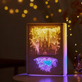 Modern three-dimensional paper carving night light with USB cable and remote control on a bedside table.