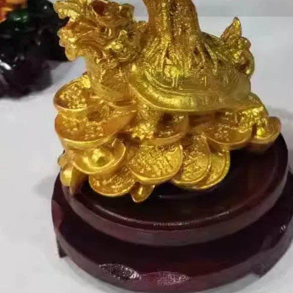 Citrine coloured resin small water turtle money tree Feng Shui ornament on a surface.