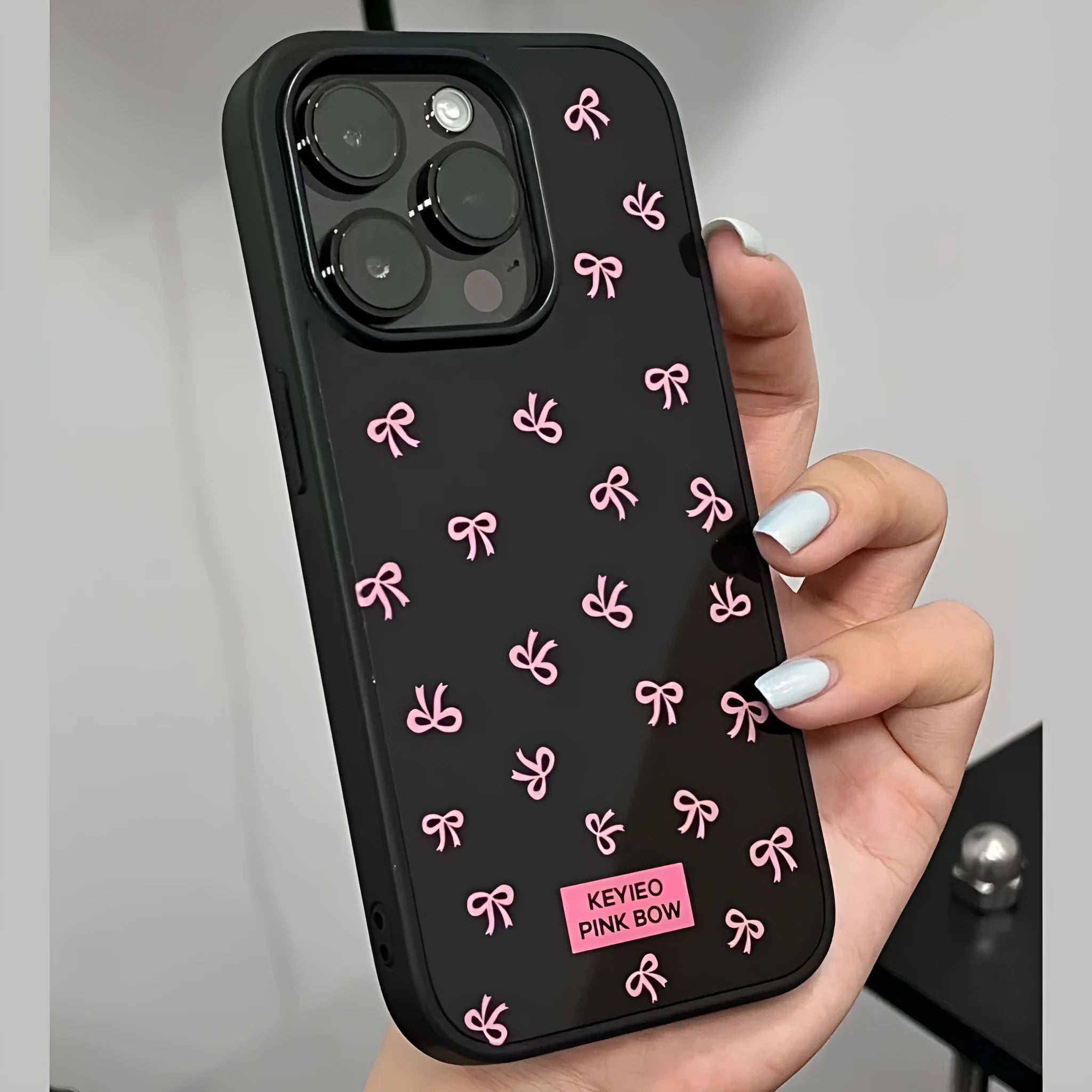 Black silicone iPhone case with sweet bow design placed on a white surface, all-inclusive back and side coverage