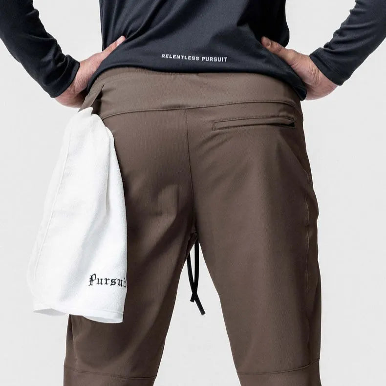 Men's loose grey running pants with ankle ties, laid flat to show mid-waist and full-length design.