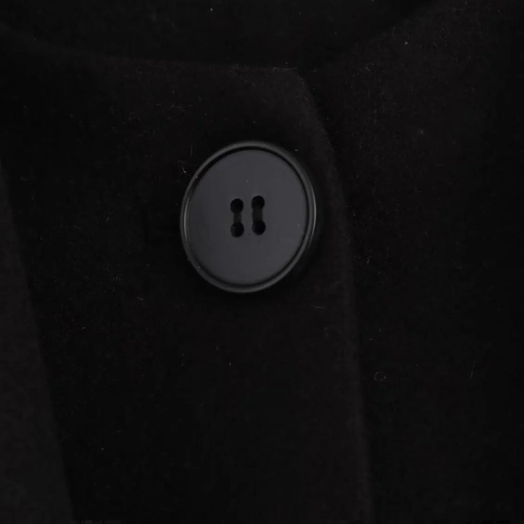 A woman wearing a long grey polyester coat with a detachable artificial fur collar and side pockets.