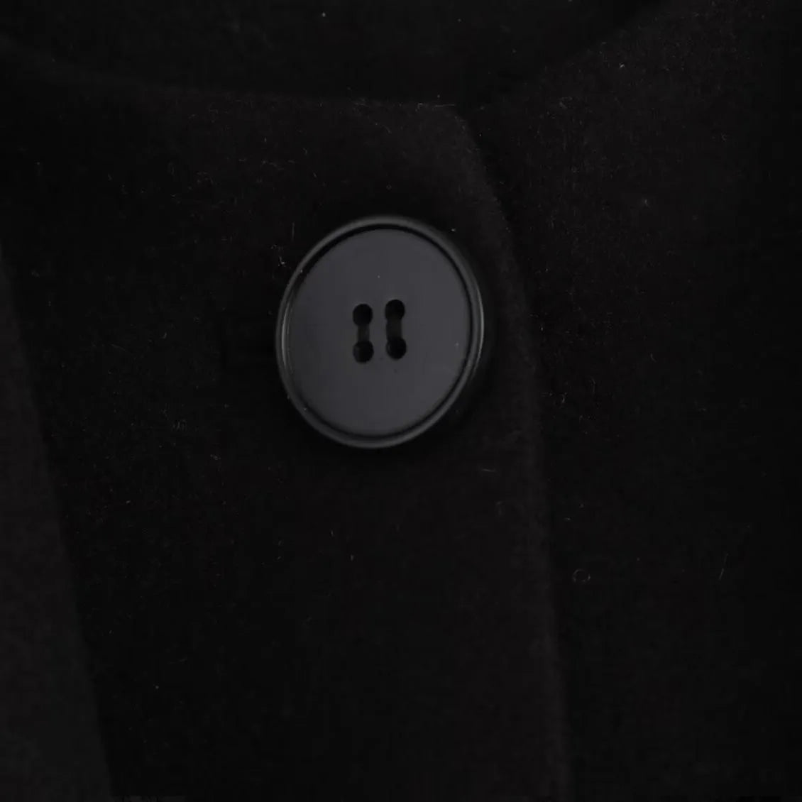 A woman wearing a long grey polyester coat with a detachable artificial fur collar and side pockets.