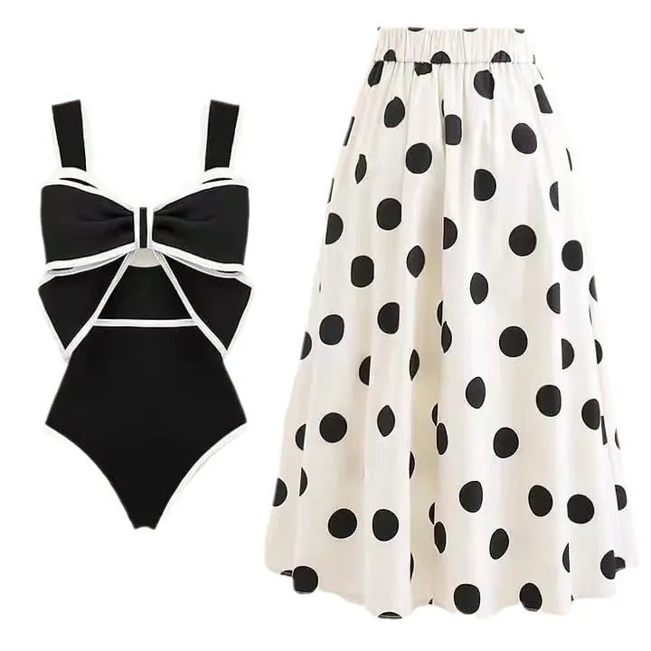 Women's black one-piece swimsuit with white skirt and bow detail on front.