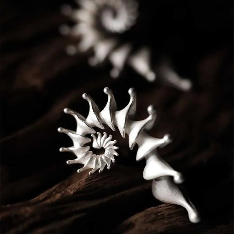 A pair of matte finish conch-coloured alloy stud earrings with a three-dimensional irregular shape.