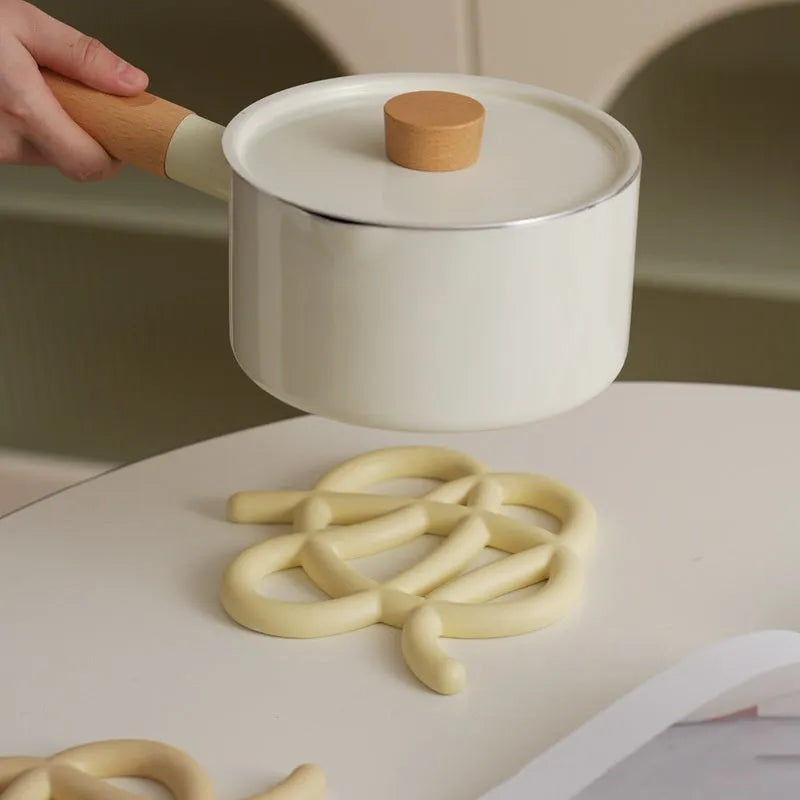 A solid colour ceramic heat proof mat with an irregular shape on a dining table.