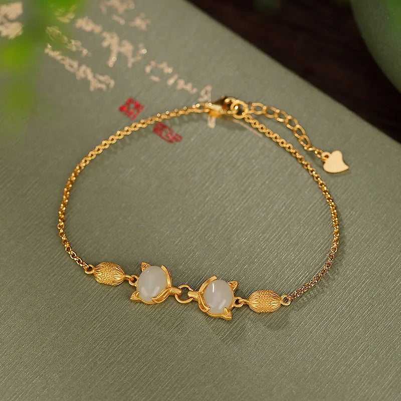 Close-up of a sterling silver fox charm bracelet with a Hetian jade stone on a model's wrist.