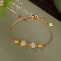Close-up of a sterling silver fox charm bracelet with a Hetian jade stone on a model's wrist.