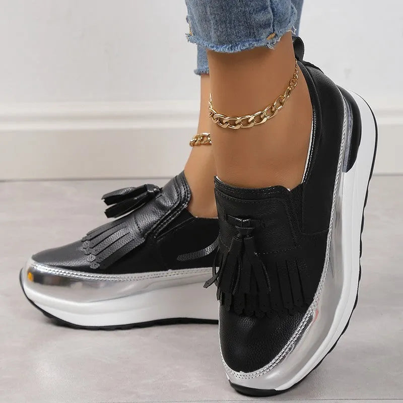Women's black casual platform shoes with tassel detail and a low wedge heel on a white background.