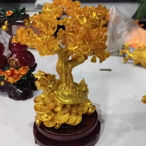 Citrine coloured resin small water turtle money tree Feng Shui ornament on a surface.