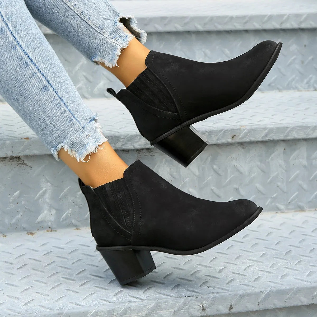 Women's black pointed toe ankle boots with thick square low heel on wooden floor