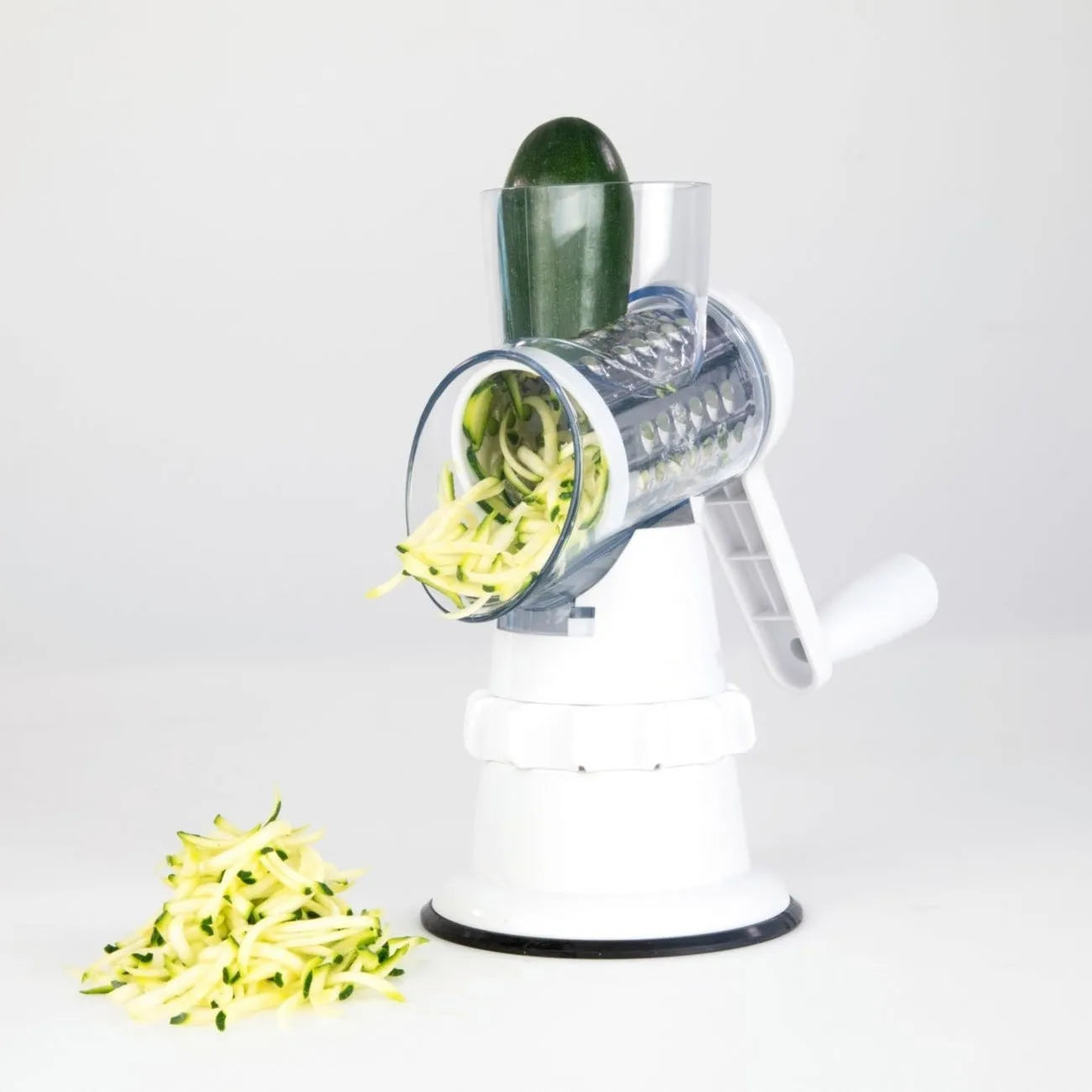 White plastic manual 3-in-1 vegetable slicer grater with stainless steel blades on a kitchen counter.
