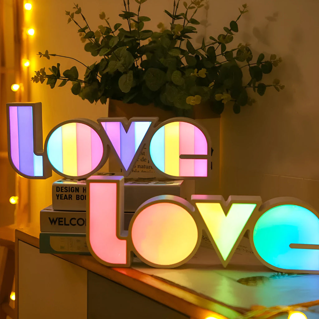 Rainbow-style plastic LED decorative light spelling LOVE, shown on a table.
