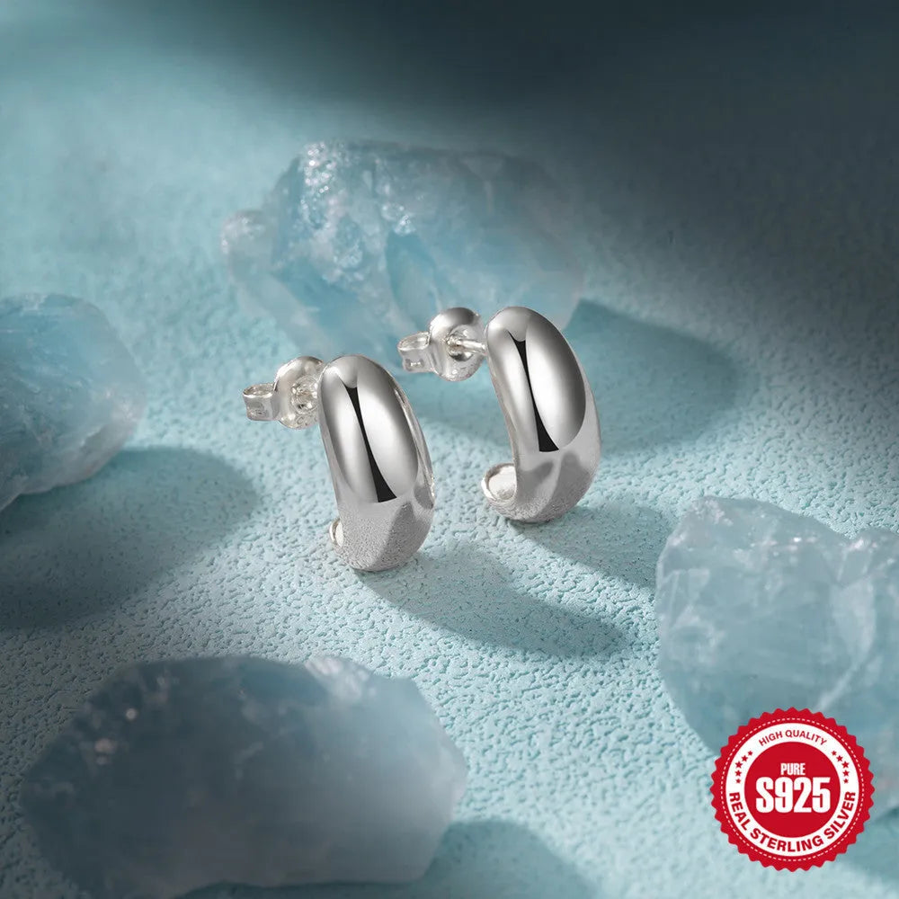 A single glossy C-shaped sterling silver stud earring on a white background.