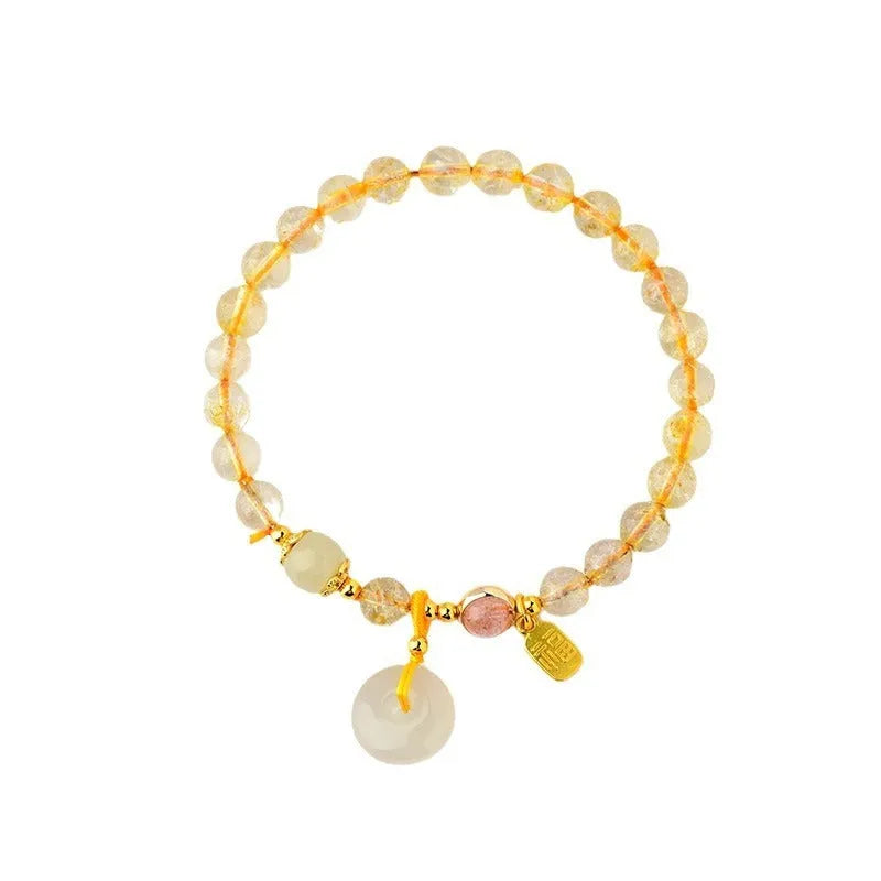 Gold rutilated quartz bracelet with geometric safety buckle and pendant on a white background.