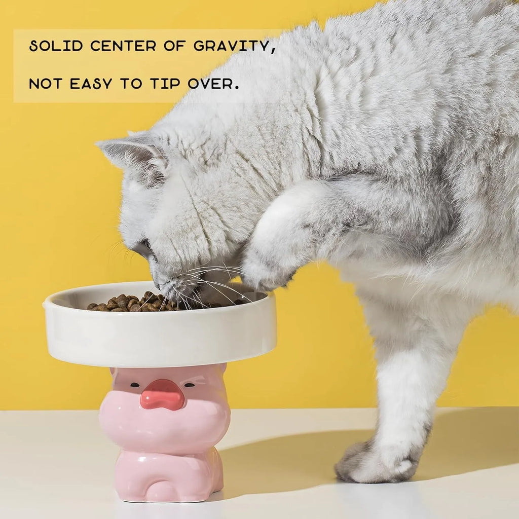White ceramic raised cat bowl with a bear design, showing its elevated stand and wide feeding dish.