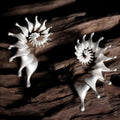 A pair of matte finish conch-coloured alloy stud earrings with a three-dimensional irregular shape.