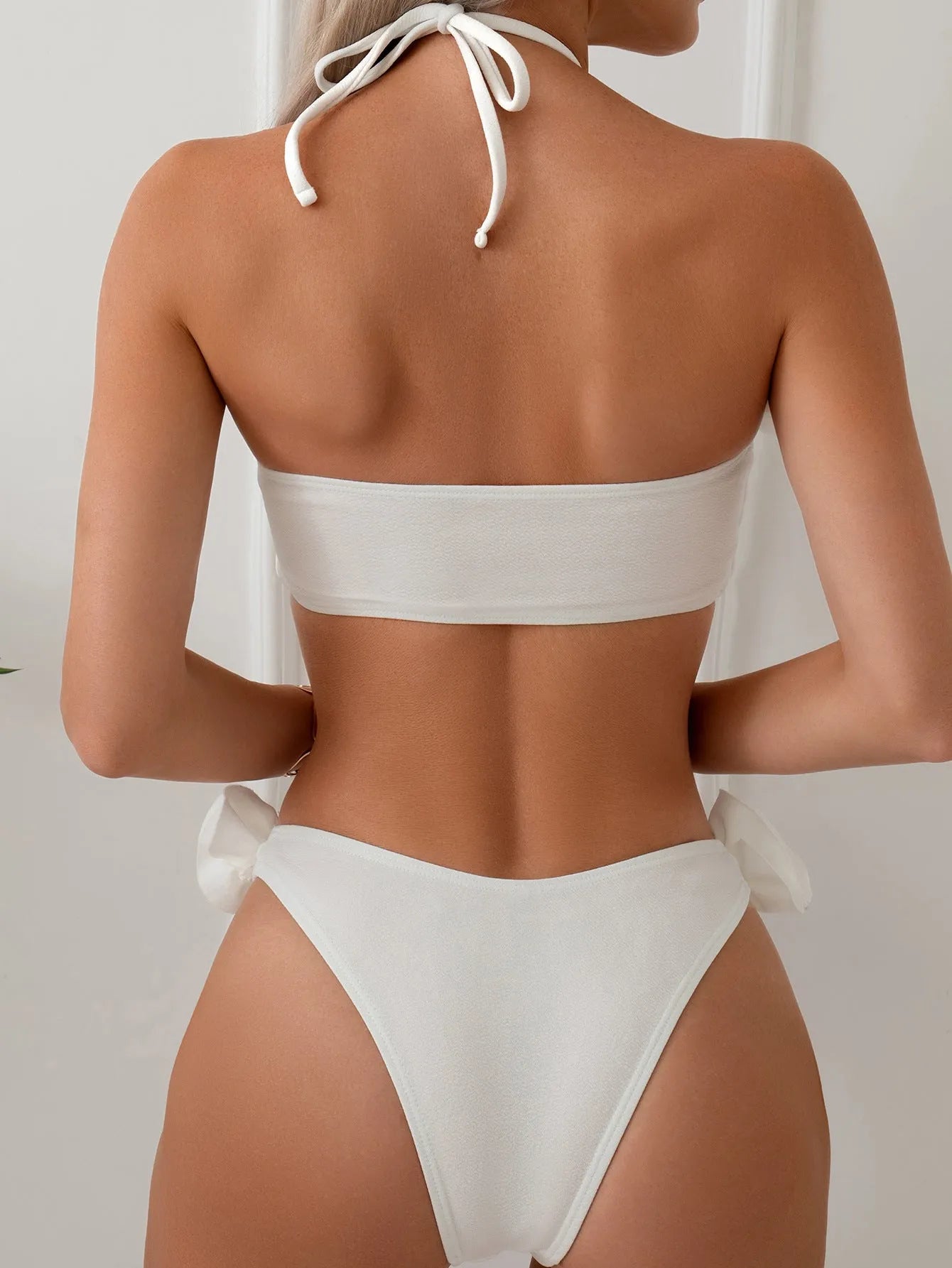 White halter neck lace-up bikini with three-dimensional floral embroidery and brief bottoms.