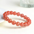 Natural cherry red agate bracelet with polished beads in a scattered design on a wrist.