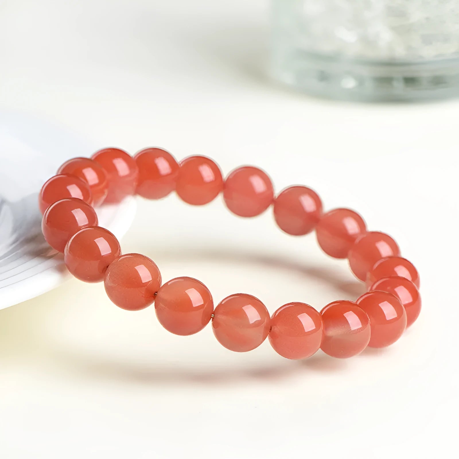 Natural cherry red agate bracelet with polished beads in a scattered design on a wrist.