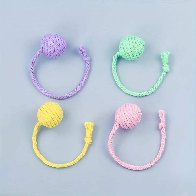 Cat toy ball with integrated rope and bell in green pink purple yellow colours