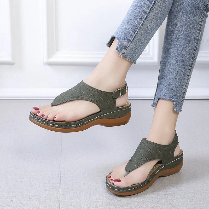 Women's red wedge heel sandals with an adjustable buckle strap on a plain background.