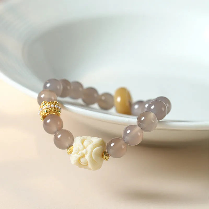 Hand-woven bracelet with large round grey agate and mellite beads on wrist.