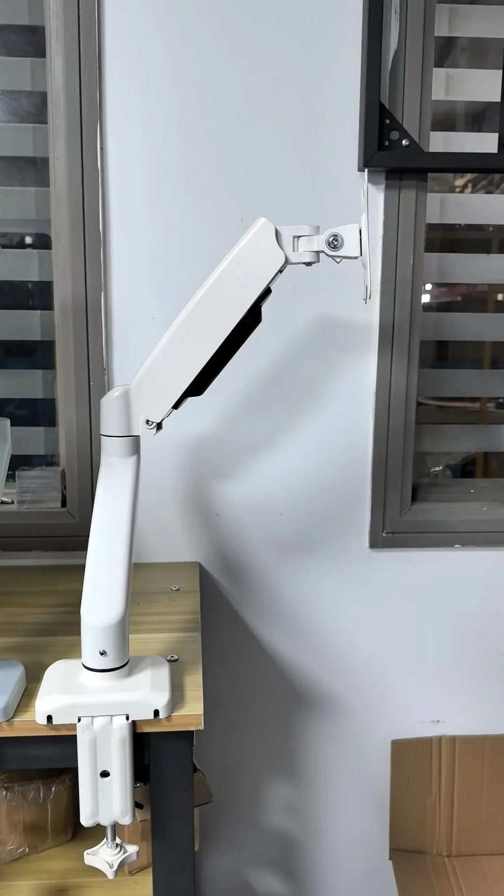 Universal black rotating telescopic LCD monitor stand on a desk next to a keyboard.