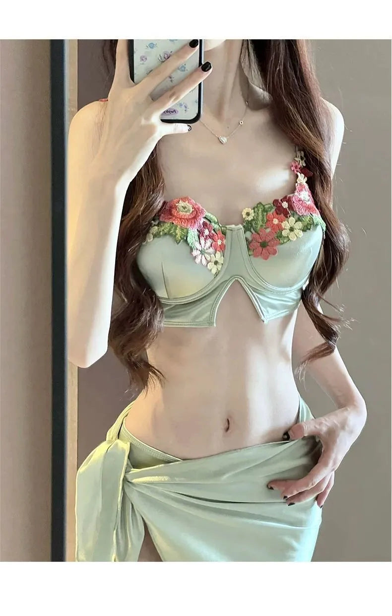 Green three-piece women's bikini swimsuit with triangle top, briefs, and skirt