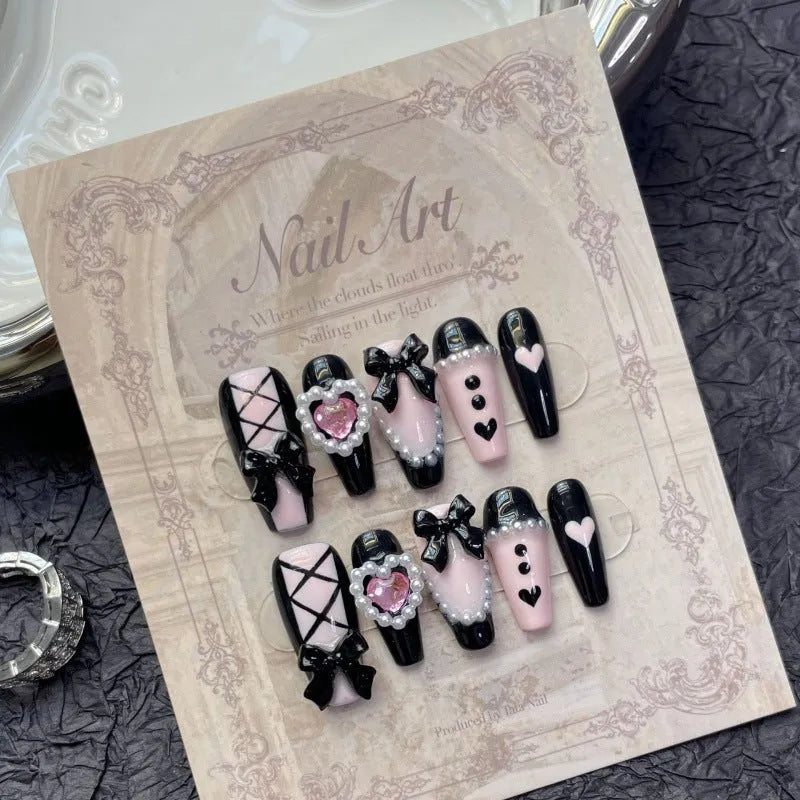 Handmade artificial nails with black and pink heart design and bow pattern in four sizes